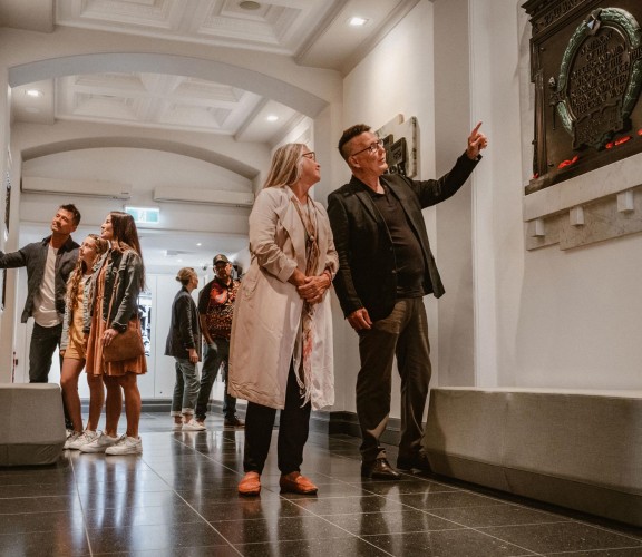 Groups of people walking through the gallery, pointing at plaques on the wall.